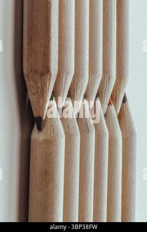 Close-up of Two groups brown crayons are placed sharp tips facing collide to each other stand in a neat row. Wooden pencils arranged in a symmetrical Stock Photo