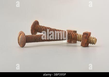 close-up of rusted bolts with nut attached isolated neutral gray background, reddish brown discolored and sings of heavy corrosion, selective focus Stock Photo