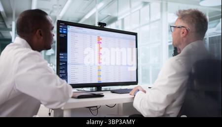 Doctors Conducting Medical Billing Audit Of Hospital Bills Using Spreadsheet. Stock Photo