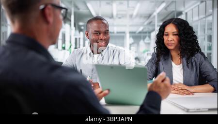 African American Real Estate Agent Assists Diverse Young Couple Stock Photo
