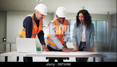 Engineers Inspecting Blueprint Of House Remodel With Client. African American Architect Stock Photo