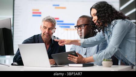Diverse Corporate Team Using Gantt And Kanban Boards For Project Management. Man And Woman Work Together In Office Stock Photo