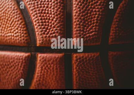 Basketball surface showing pebble-grain leather and black seams in flat design, dark background Stock Photo
