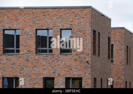 Red brick facade of a modern building showcasing sustainable architecture and incorporating energy-efficient windows Stock Photo