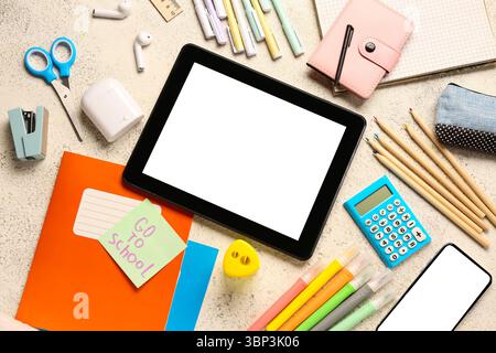 Sticky note with text GO TO SCHOOL, gadgets and different stationery on grunge white background Stock Photo