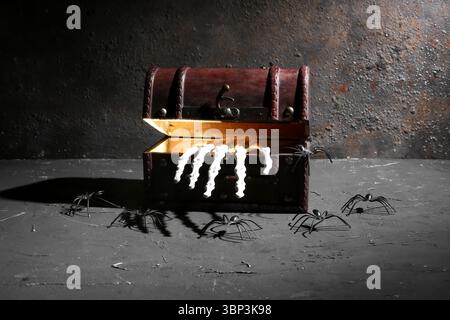 Old treasure chest with skeleton hand and spiders on dark background. Halloween celebration Stock Photo
