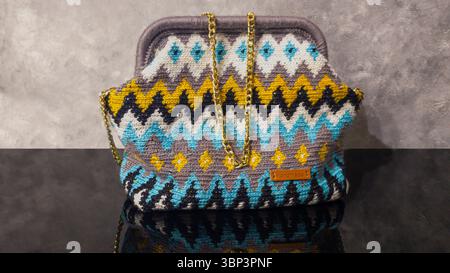 Bag crocheted from multi-colored threads. Yellow with gray, black and other colors in jacquard knitted fabric. Handmade Stock Photo