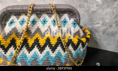 Bag crocheted from multi-colored threads. Yellow with gray, black and other colors in jacquard knitted fabric. Handmade Stock Photo
