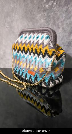 Bag crocheted from multi-colored threads. Yellow with gray, black and other colors in jacquard knitted fabric. Handmade Stock Photo