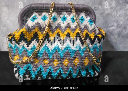 Bag crocheted from multi-colored threads. Yellow with gray, black and other colors in jacquard knitted fabric. Handmade Stock Photo