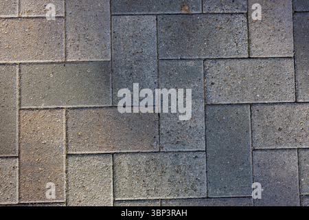 Interlocking rectangular pavers form a herringbone pattern on a walkway. Subtle shadows create a play of light and texture across the surface. Stock Photo