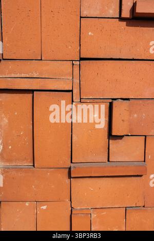 Neatly stacked redish bricks form random geometrically visually appealing wall. Bricks' earthy tones enhances their textures, adding natural feeling. Stock Photo