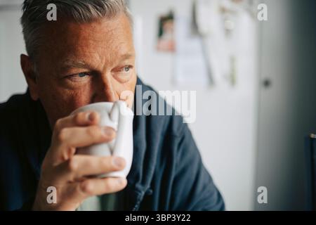 Thoughtful elderly man drinking coffee at home Stock Photo