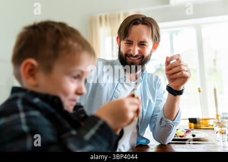 Happy father sitting next son playing at home Stock Photo