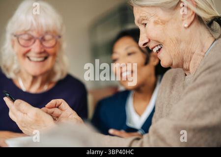 Happy senior woman using smart phone while spending leisure time in retirement home Stock Photo
