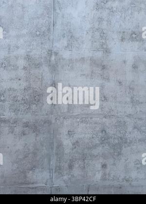 The image shows a close-up of a raw grey concrete wall. The surface reveals formwork lines and natural marks from the casting process, giving it a rou Stock Photo