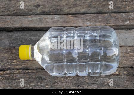 Plastic water bottle with yellow cap lying on rustic wooden surface Stock Photo