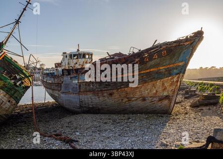 Close-up view of a decaying fishing boat stranded on the pebbled shore of the Camaret-sur-Mer shipwreck graveyard, Finistère, Brittany, France, at low Stock Photo