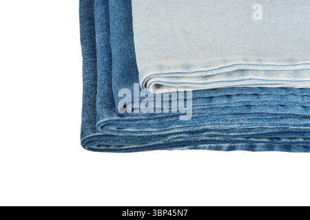 Pile of folded textiles, various shades of blue jeans fabric isolated on white background. Denim cloth stacked in store setting, different textures an Stock Photo