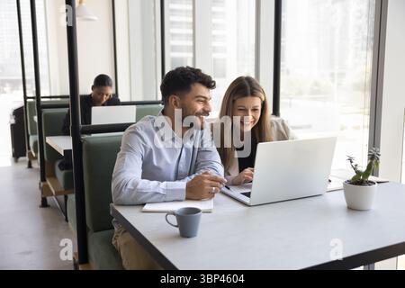 Happy pair of businesspeople work together in coworking using notebook Stock Photo