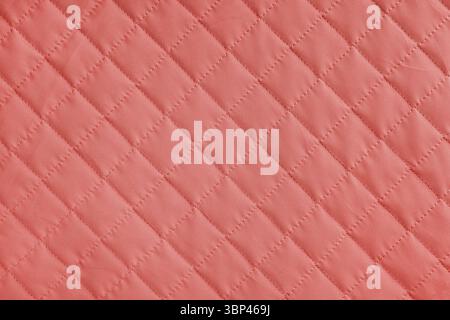 Checkered, diamond stitching pattern, red quilted fabric background. Blanket or puffer jacket, stitch rhombus texture close up, macro. Wallpaper, back Stock Photo