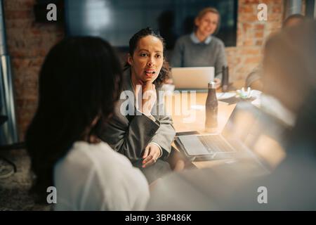 Businesswoman with hand on chin discussing in meeting at work place Stock Photo
