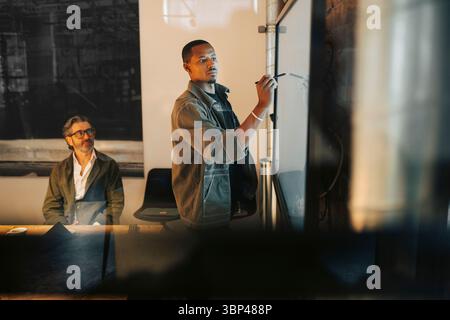 Male entrepreneur writing ideas on screen in meeting at office Stock Photo
