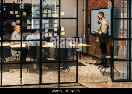 Businessman giving presentation to colleagues sitting in conference room Stock Photo