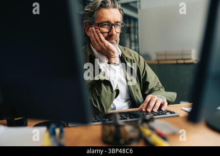 Bored senior businessman working on desktop PC at office Stock Photo