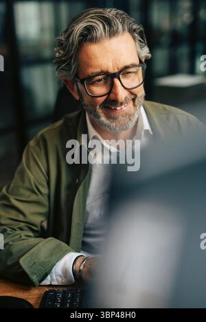 Smiling elderly businessman working on computer at office Stock Photo