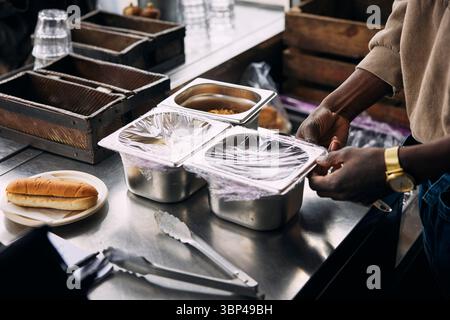 Man removing plastic from top of container in food truck Stock Photo