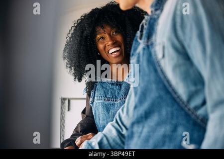 Happy curly haired woman wearing apron talking with coworker in food truck Stock Photo