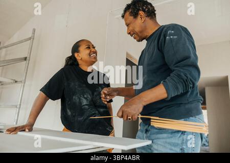 Low angle view of smiling male and female construction workers talking with each other while working at construction sit Stock Photo
