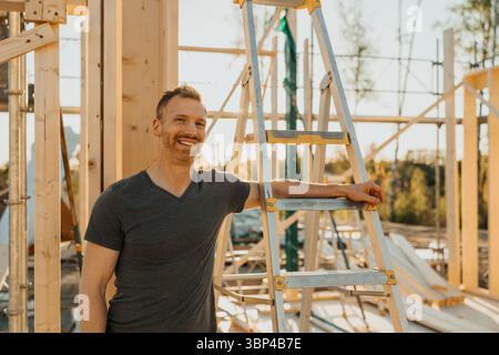Portrait of mature man standing next to ladder at under construction house Stock Photo