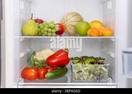 Assorted produce neatly arranged on refrigerator shelves Stock Photo