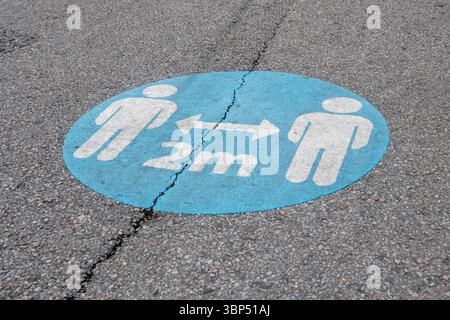 Social Distancing Sign – 2 Metre COVID-19 Safety Marking on Pavement Stock Photo