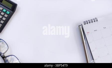 Minimalist flat lay workspace featuring pen, calendar, eyeglasses, calculator on white. Ideal for business, planning, productivity, time management, d Stock Photo