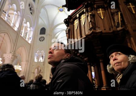 Two tourists looking up to the nave vaults with the pulpit in the background inside Norte-Dame Cathedral of Paris after the reopen of the fire of April 2019.Paris.France Stock Photo