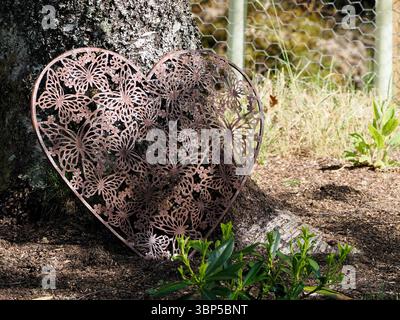 Heart Shaped Garden Feature, made from wrought iron and  sat against the base of a Beech Tree Stock Photo