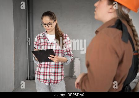 Building, home renovation concept. Construction inspector and apartment owner discussing design plan with contractor during reading project of Stock Photo
