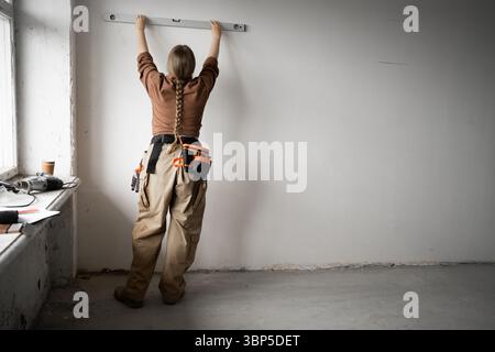 Handyman measuring wall with spirit level. Repairman working home renovation and construction. Stock Photo