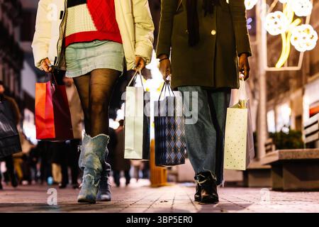 Close-up of women carrying shopping bags on festive winter street. Christmas. Celebration. Stock Photo