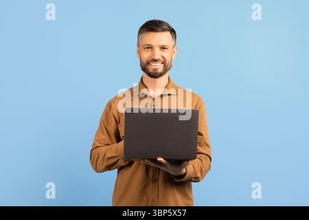 Confident young man smiling and holding laptop in hands Stock Photo