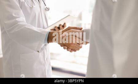 Two doctors in lab coats handshake close up Stock Photo