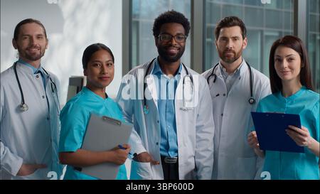 Happy smiling professional multiethnic diverse doctors people medicare team portrait five interns men women talking discuss health exam result looking Stock Photo