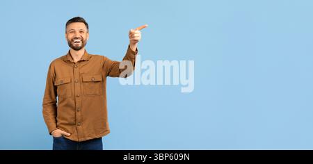 Happy young man pointing upward at copy space and laughing Stock Photo