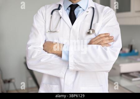 Unrecognizable male doctor in lab coat keeping arms folded Stock Photo