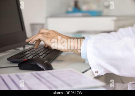 Hands of doctor typing on keyboard at desktop monitor Stock Photo