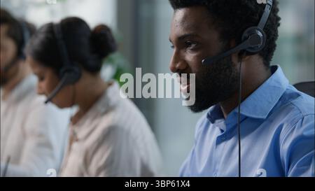 Call center helpline workers headset typing keyboard computer business service African American Indian Caucasian operators multiethnic three Stock Photo