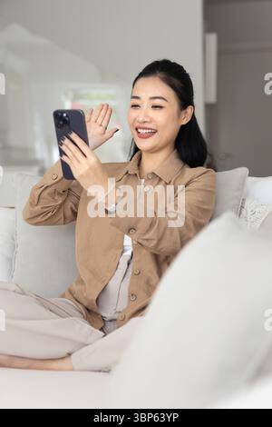 Happy Asian woman start videocall using her modern smartphone Stock Photo